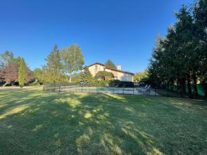 a large grass field with a house in the background at Villa d'architecte 200m² avec piscine privée et cheminée - FR-1-496-35 in Pommiers-en-Forez