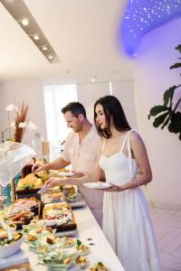 a man and a woman standing in front of a buffet at The St. Regis Bal Harbour Resort in Miami Beach