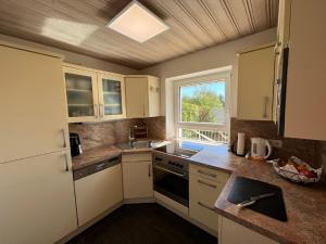 バート・ケッツティングにあるFerienhaus Liebensteinの白いキャビネット、シンク、窓付きのキッチン