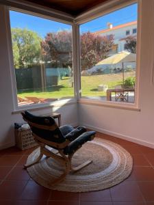 un fauteuil à bascule assis devant une fenêtre dans l'établissement Sunny Villa Minutes from the Beach, à Lourinhã