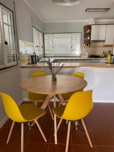 une cuisine avec une table en bois et des chaises jaunes dans l'établissement Sunny Villa Minutes from the Beach, à Lourinhã