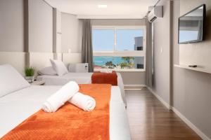 Cette chambre comprend deux lits et une grande fenêtre. dans l'établissement Boulevard Beach Canasvieiras Hotel, à Florianópolis