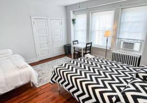 Schlafzimmer mit einem schwarzen und weißen Bett und einem Schreibtisch in der Unterkunft Legacy - Spring Garden University City in Philadelphia