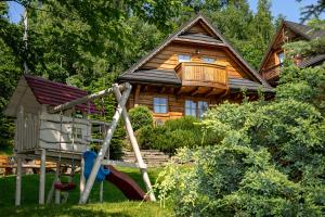 a log cabin with a swing and a house at Kotelnica Resort in Międzybrodzie Bialskie