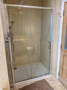 La salle de bains est pourvue d'une douche avec une porte en verre. dans l'établissement 47 High Street, à Alness