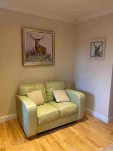 a green couch in a room with a picture of a deer at 47 High Street in Alness