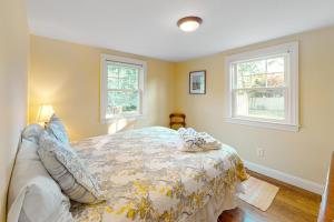a bedroom with a bed and two windows at Cape Escape in West Yarmouth