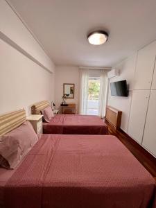 a hotel room with two beds and a television at Red Apartment wt Indoor Parking near Marousi Hospitals, by PromosHomes in Athens
