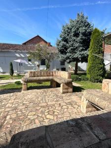 a stone patio with two benches in a yard at Sobe Šponga 4, in Kikinda