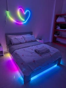 ein Schlafzimmer mit einem Bett mit einem Herz-Neon-Licht in der Unterkunft Elegant Studio in New Atlit with Garden & BBQ, 3 Min to Beach, Free Netflix in Atlit