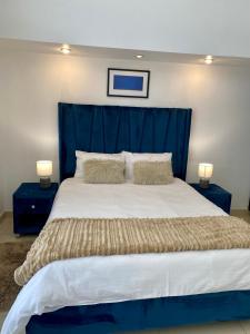 1 cama grande con cabecero azul y 2 mesitas de noche en Catalea's Cousy home en Windhoek