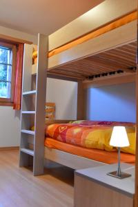 ein Schlafzimmer mit Etagenbetten, einer Lampe und einem Tisch in der Unterkunft Haus Brunnen (Anton Karlen) in Riederalp