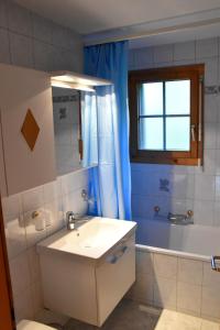 ein Bad mit einem Waschbecken, einer Badewanne und einem Fenster in der Unterkunft Haus Brunnen (Anton Karlen) in Riederalp