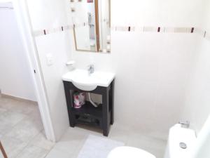 Monoambiente las lilas في بويرتو مادرين: حمام أبيض مع حوض ومرآة