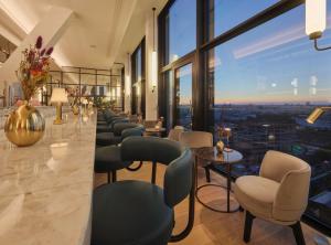 un bar con sedie e tavoli in una stanza con finestre di Adina Apartment Hotel Munich a Monaco
