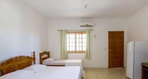sypialnia z 2 łóżkami, oknem i lodówką w obiekcie hotelCoxipóoyo w mieście Cuiabá