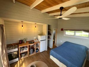 a bedroom with a blue bed and a kitchen at Amphibias in Punta Del Diablo