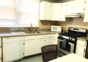 cocina con armarios blancos, fogones y fregadero en Clover 2900 - Apartment and Rooms with Private Bathroom near Washington Ave South Philly en Filadelfia