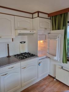 een keuken met witte kasten en een open koelkast bij Ferienwohnung direkt am Strand in Makkum in Makkum