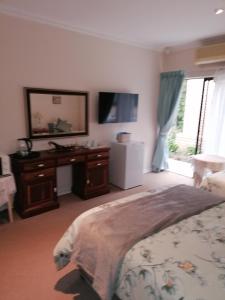 a bedroom with a bed and a desk and a mirror at Clivia Guesthouse in Pietermaritzburg