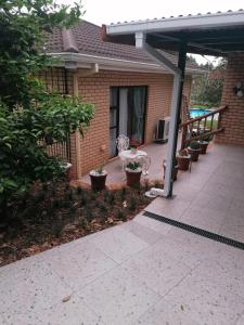 a patio with a table and potted plants in front of a house at Clivia Guesthouse in Pietermaritzburg