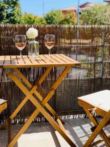 une table en bois avec deux verres de vin sur une clôture dans l'établissement T2 Cosy climatisé 5 min aéroport, à Blagnac