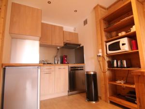uma cozinha com armários de madeira e um frigorífico de aço inoxidável em Appartement Huez, 3 pièces, 6 personnes - FR-1-405-172 em Alpe-dʼHuez