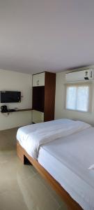 Un dormitorio con una cama grande y una ventana en Clapping Leaves Resort, en Hyderabad