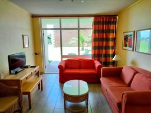 ein Wohnzimmer mit einem roten Sofa und einem TV in der Unterkunft Brookes Hill 1 Bedroom in Summerstrand