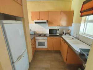 eine Küche mit Holzschränken und einem weißen Kühlschrank in der Unterkunft Brookes Hill 1 Bedroom in Summerstrand