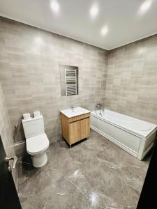 een badkamer met een bad, een toilet en een wastafel bij Confort City Residence in Popeşti-Leordeni