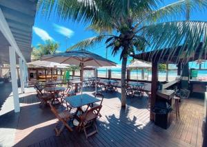 a deck with tables and chairs and an umbrella at Pousada Kai in Itanhaém