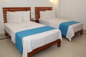 2 Betten mit weißer und blauer Bettwäsche in einem Zimmer in der Unterkunft HOTEL Casa cesar in Tumbes