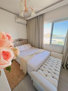 a bedroom with a bed and a couch and a window at Apartamento de frente para o Mar in Vitória