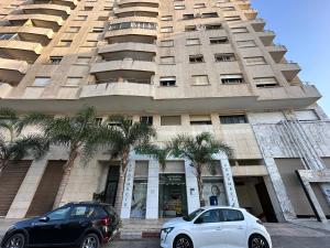 two cars parked in front of a tall building at LovelyStay - Luxury & proximity to Corniche and TGV in Tangier