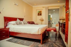 a bedroom with a large bed and a bathroom at Shangri-la Hotel Muyenga in Bugolobi