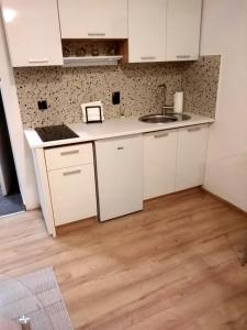 cocina con armarios blancos y suelo de madera en North&South Apartments en Zagreb