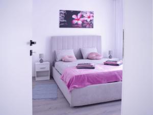 1 dormitorio blanco con 1 cama con sábanas rosas en North&South Apartments en Zagreb