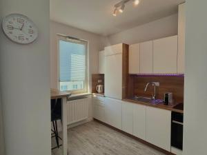 a kitchen with white cabinets and a clock on the wall at Studio Apartment Raspberry by Galeria Północna in Warsaw