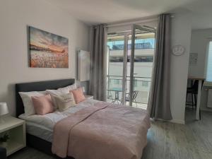 a bedroom with a bed with pink pillows and a balcony at Studio Apartment Raspberry by Galeria Północna in Warsaw