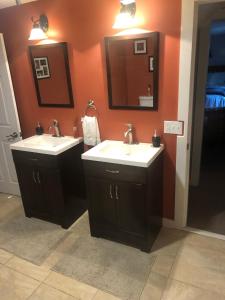a bathroom with two sinks and a mirror at Plush garden level apartment near Stowe in Morristown