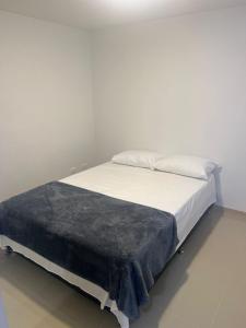 - un lit blanc avec une couverture noire dans l'établissement Hermoso Apto con Vista al Ciudad y Parqueadero Gratis, à Bello