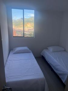 - 2 lits dans une petite chambre avec fenêtre dans l'établissement Hermoso Apto con Vista al Ciudad y Parqueadero Gratis, à Bello