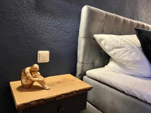 una estatua de un hombre sentado en una mesa junto a una cama en #Stadtspeicher - Blauer Stern das Apartment mitten in der Altstadt, en Rothenburg ob der Tauber