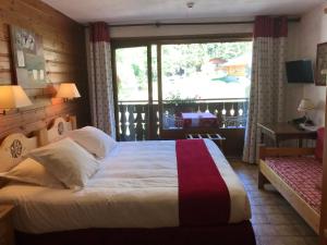 a bedroom with a bed and a large window at Au Bois de Lune in Châtel
