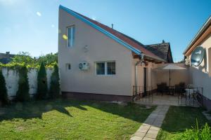 een klein wit huis met een patio en gras bij Apartmani Kačara in Sremski Karlovci