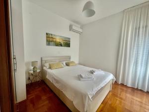 a white bedroom with a bed with two towels on it at Acacia Hills B1 in Đenovići +11 photos