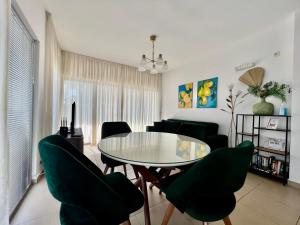 a dining room with a glass table and green chairs at Acacia Hills B1 in Đenovići