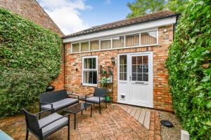 un edificio de ladrillo con una puerta blanca y sillas en Fifth Milestone Annexe en York