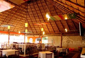a restaurant with tables and chairs and a straw ceiling at Las Magnolias Hotel Boutique in San Salvador